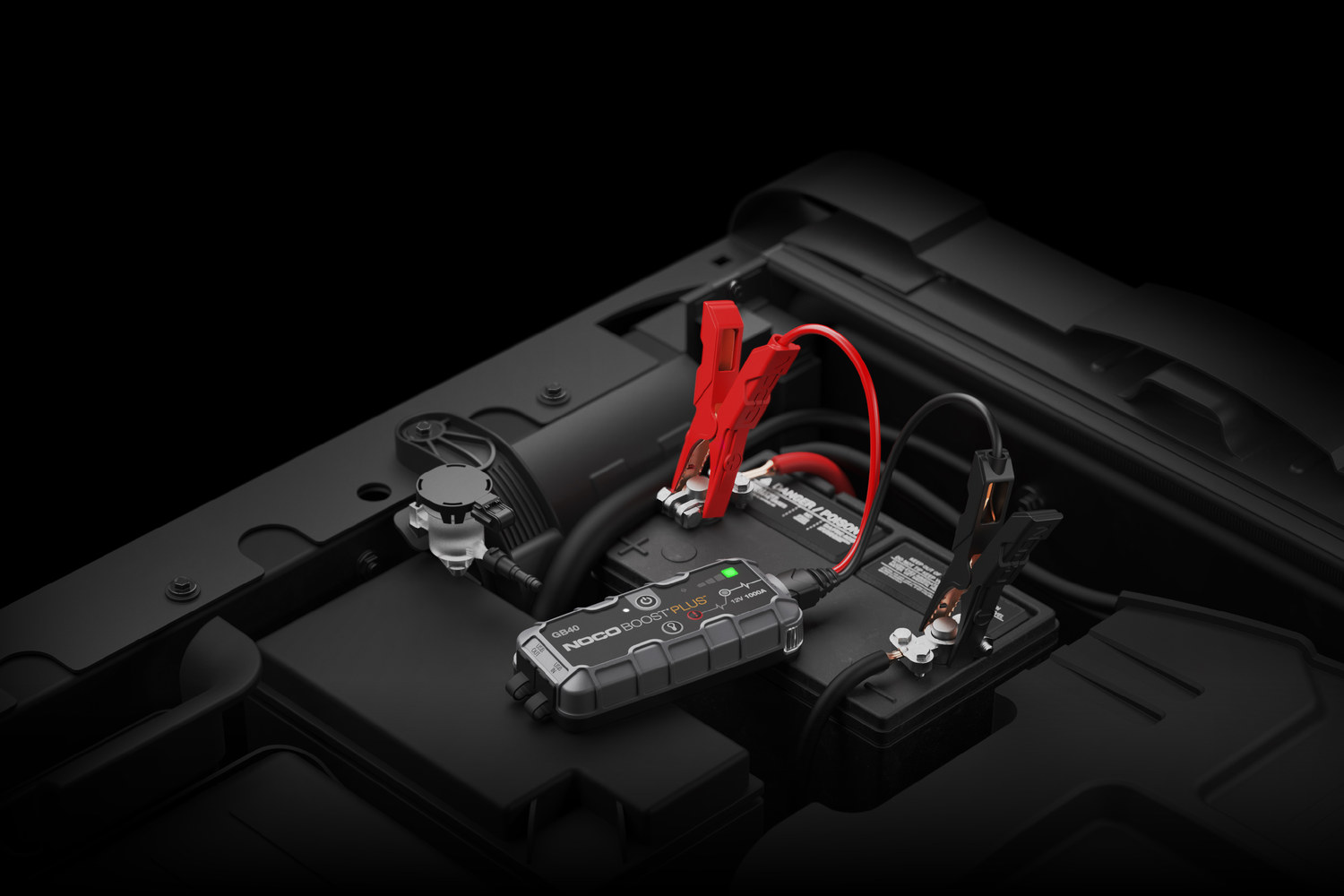 NOCO GB40 jumpstarter aangesloten op de startaccu in een motorruimte
