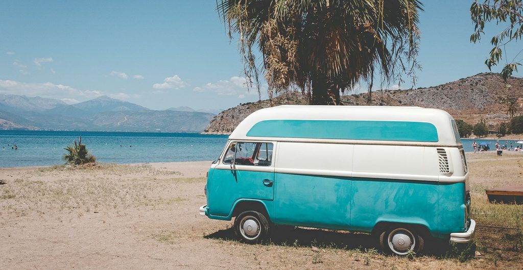 Turquoise Volkswagen-bus onder een palmboom aan het strand bij Nafplio