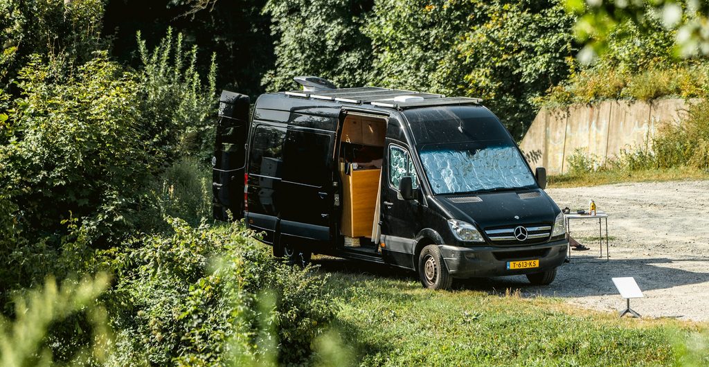 Zwarte buscamper met open schuifdeur tussen het groen bij Stari Grad op het eiland Hvar