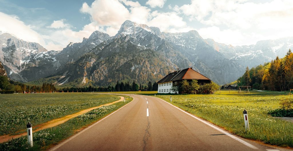 Rechte weg door groene weiden naar de bergen bij de Almsee in Opper-Oostenrijk