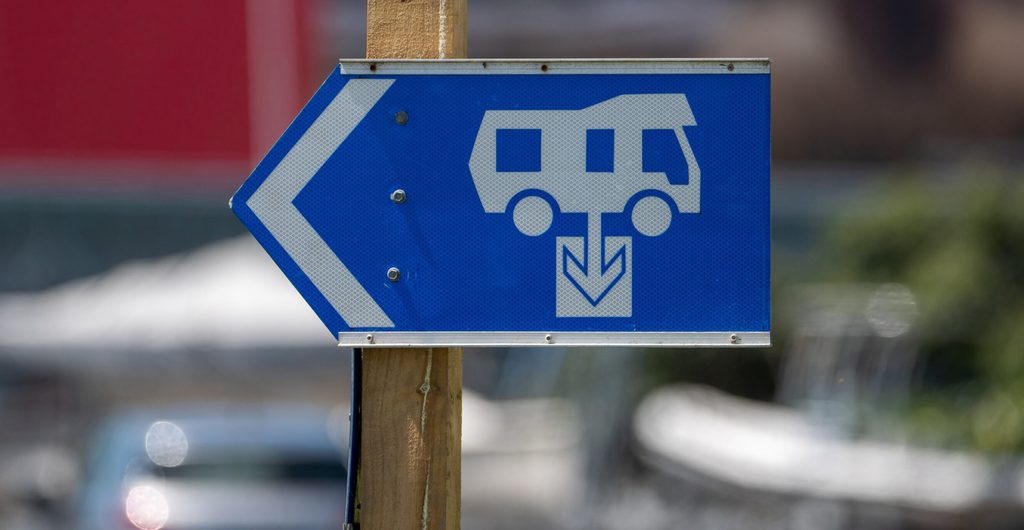 Blauw bord met een camper-pictogram en een pijl naar het lospunt voor het legen van een chemisch toilet op een servicepunt