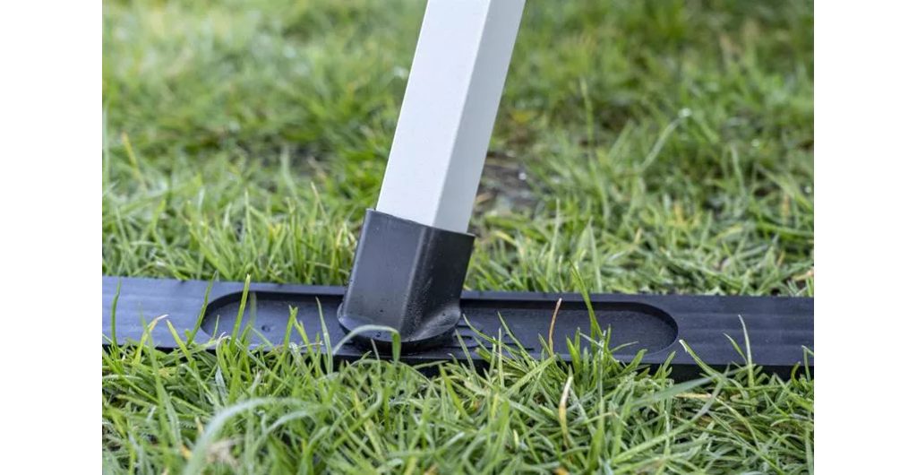 Poot van een aluminium opstapje op een zwarte Haba onderzetplank in het gras, zodat hij niet wegzakt