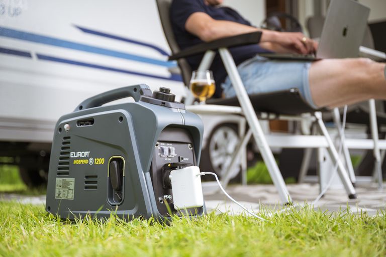 Stille aggregaat bij de camper: Eurom Independ 1200 inverteraggregaat op het gras laadt een laptop op de camping