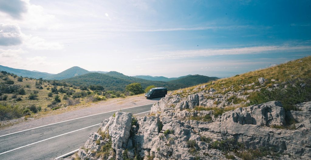 Donkere bus op een bochtige weg door het karstlandschap bij &Scaron;krljevo boven Rijeka