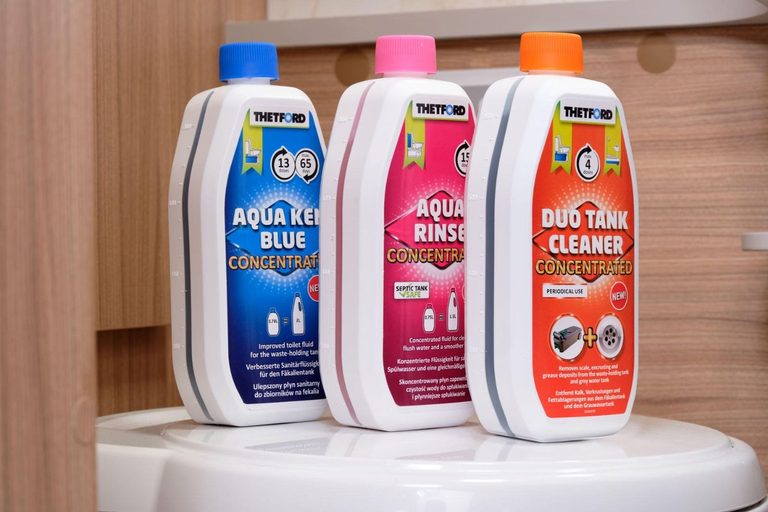 Vloeistof voor chemisch toilet: flessen Aqua Kem Blue, Aqua Rinse en Duo Tank Cleaner van Thetford op de deksel van een cassettetoilet
