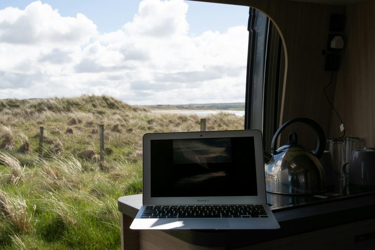 Wifi versterker camper: laptop op het aanrecht van een camper met uitzicht op de duinen